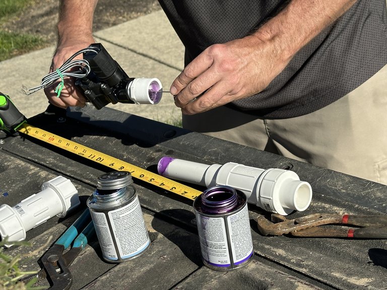 Hands preparing a fitting on a replacement irrigation valve assembly